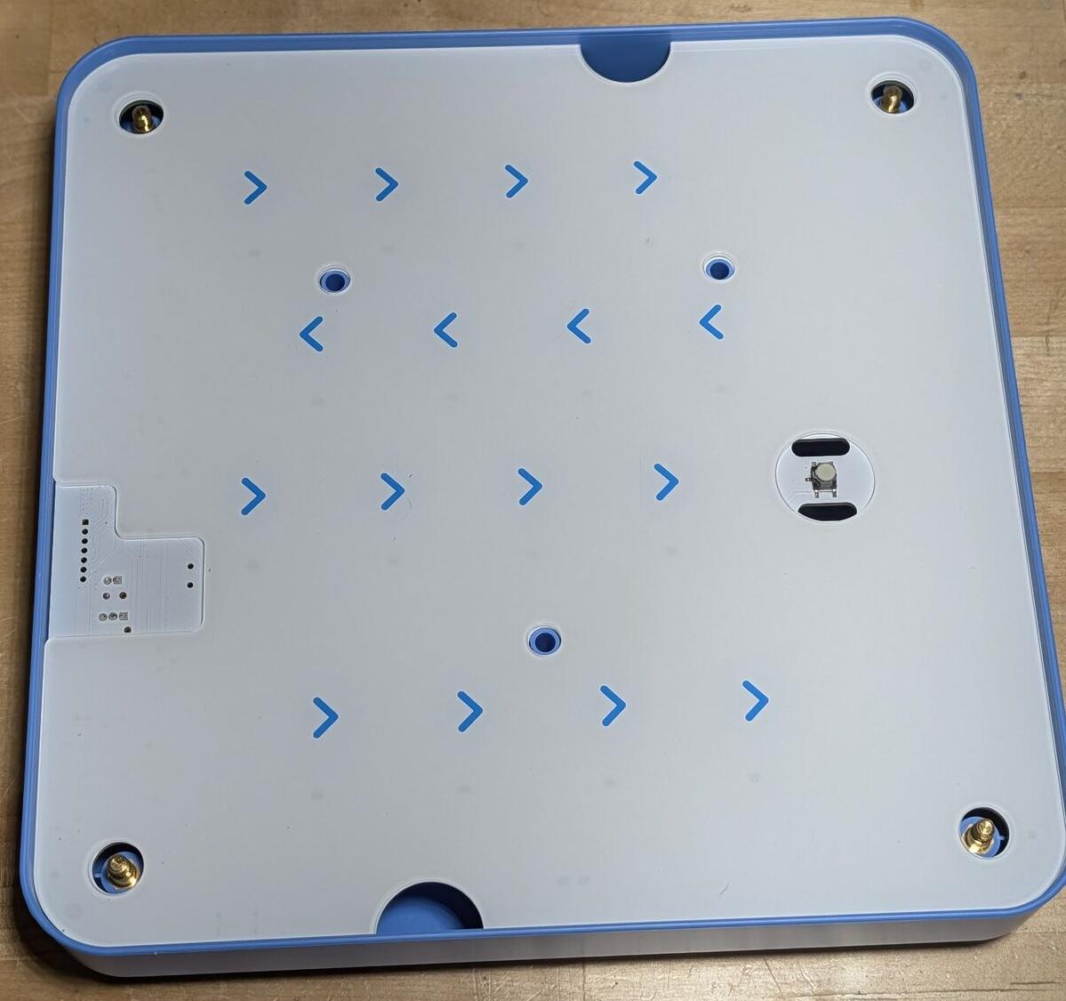 Plexiglass layer with printed chevron arrows marking each tile slot position.