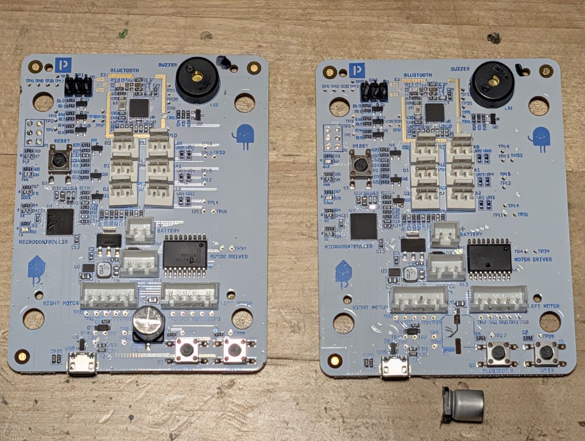 Two replacement robot PCBs, both marked v2.14. One arrived with a capacitor rattling loose inside the FedEx envelope.